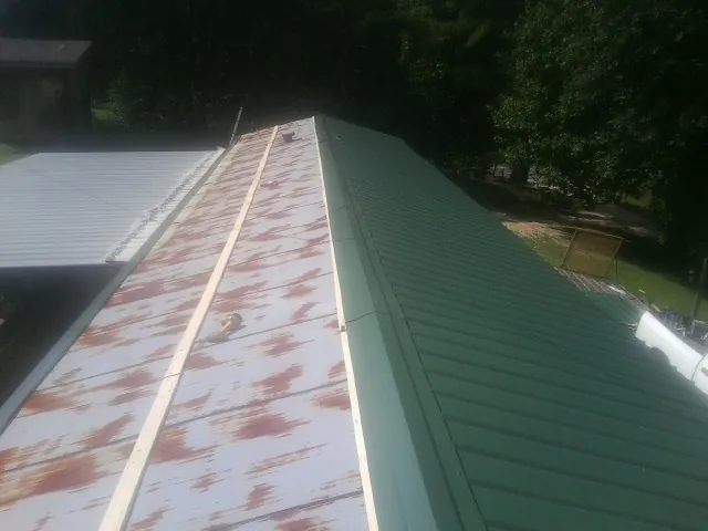Old rusted panels beside newly installed green metal roofing — Wind Damage Roof Repair by Roofing Brothers in Schaghticoke