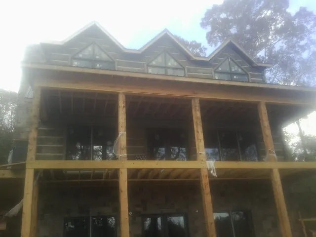Dormers and porch framing on a large log home under construction — Roof Coating work by our crew in Schaghticoke
