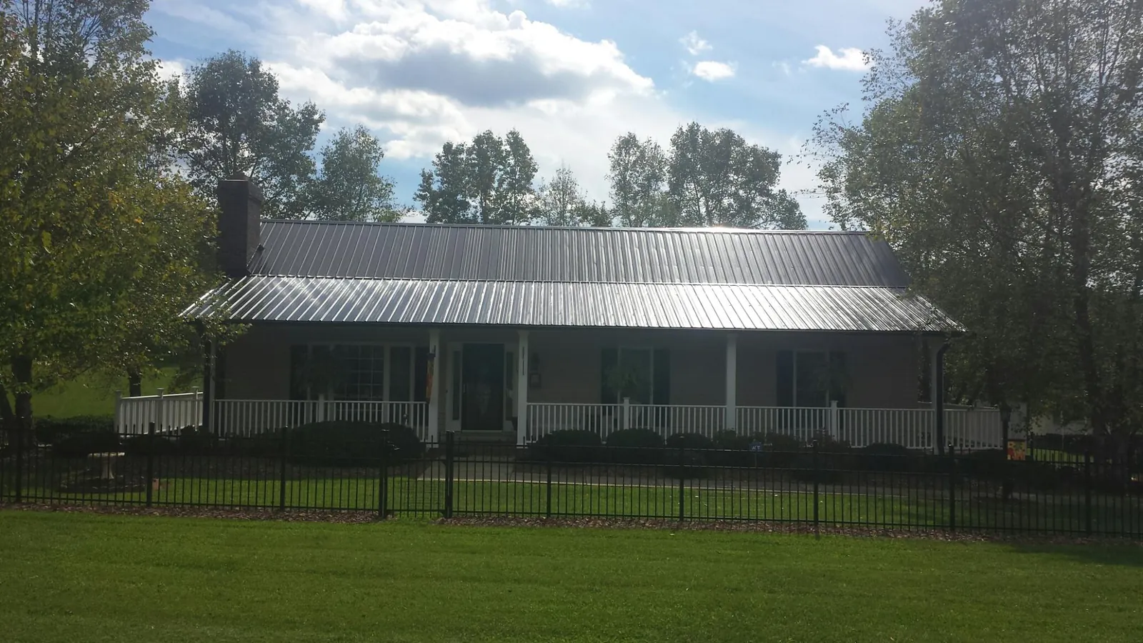 Gray metal roof on a brick ranch with a full width front porch — Gutter Guard Installation work by our crew in Schaghticoke
