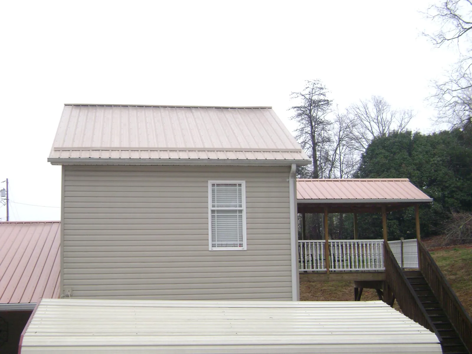 Tan metal roofs on a two story addition and attached porch, from a Roof Replacement job in Schaghticoke