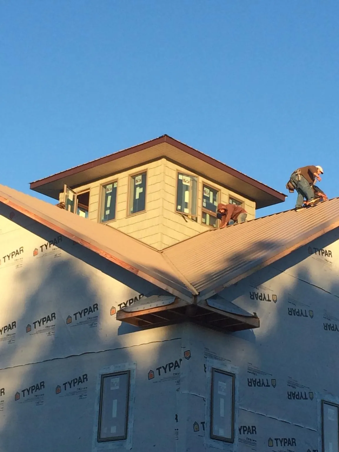 Roofers working around a rooftop cupola on a new metal roof at sunset — Roof Waterproofing in Schaghticoke by Roofing Brothers